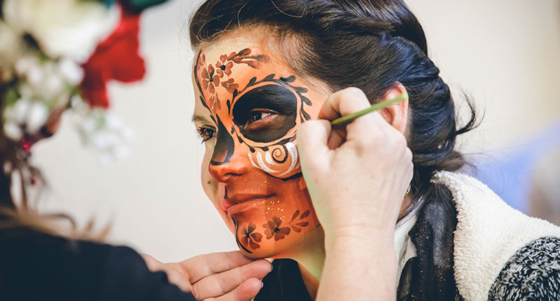 Woman having her face painted at Dia De Los Muertos celebration in Breckenridge